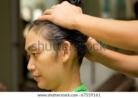 Asian ethnic young woman having hair massage at salon