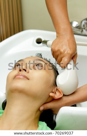Asian ethnic young woman having hair wash at hairdressing salon
