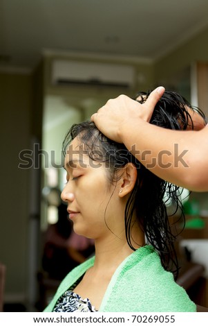 Asian ethnic young woman having hair treatment at hairdressing salon