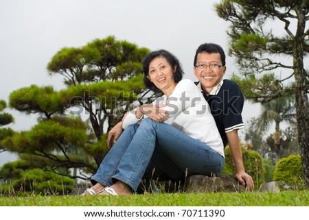 Asian ethnic family portrait of mature couple posing in the park