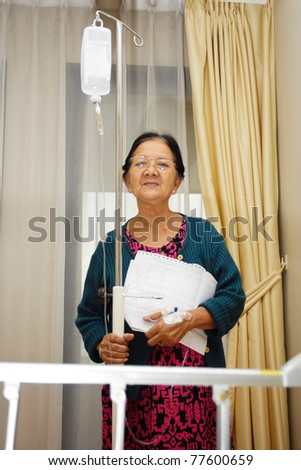 asian ethnic sick senior patient portrait in hospital ward holding lab result