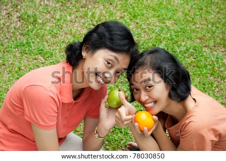two happy asian ethnic sisters showing their love of tropical fruits