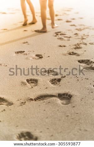 people walk on the beach with foot print behind