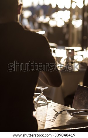 silhouette of a waiter serve banquet tables at outdoor restaurant