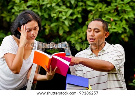 asian ethnic young man and woman sitting on a ladder discuss their study