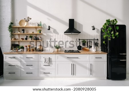 Modern kitchen interior with white furniture, appliances, decor and black refrigerator. Bright and spacious Dining room. Luxury apartment design project  Сток-фото © 