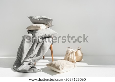 Plaid in wicker basket, clean blanket, linen bedding, cotton sheets, pillow, cushion and duvet with natural material on chair after laundry, copy space. Washing, housekeeping, hotel service concept Stockfoto © 