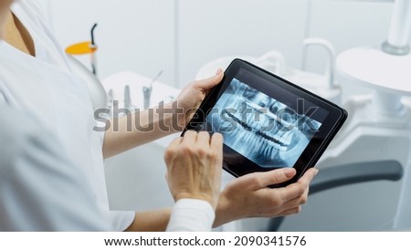 Cropped shot of professional dentist showing jaws and teeth x-rays to her patient, using a digital tablet technology, discussing a treatment plan while they standing in stomatology clinic, web banner Stock foto © 