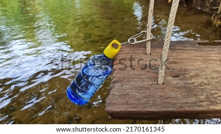 dark blue plastic water bottle It has a yellow cap which has a hole for a loop and a clip to attach to the swing rope. when doing outdoor activities  ストックフォト © 