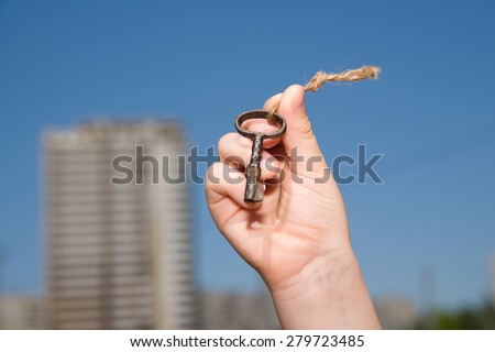 Child hand holding an old keys on a string against the sky
