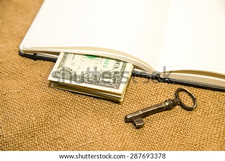 Opened notebook with a blank sheet, key and money on the old tissue