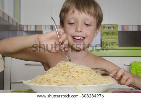 Small boy eating spaghetti with fork and smiles.