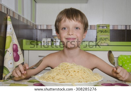 Small boy eating spaghetti with fork and smiles.