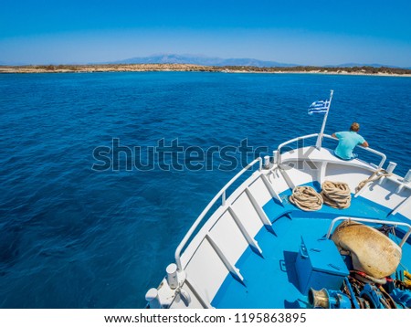 Greek flag waving on the bow of a boat sailing toward the island of Chrissi. The uninhabited island of Chrissi is available only by boat, an hour of cruise from Ierapetra, south of Crete.