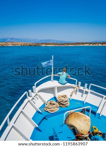 Greek flag waving on the bow of a boat sailing toward the island of Chrissi. The uninhabited island of Chrissi is available only by boat, an hour of cruise from Ierapetra, south of Crete.