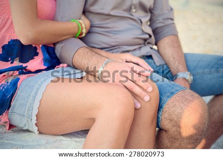 Loving couple arm, sitting on a bench on top of a marble quarry in Carrara, he strokes her knee