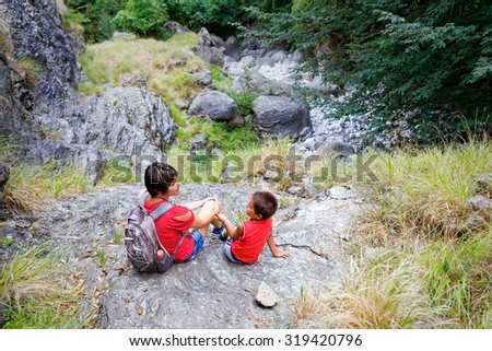 Mother and child on the edge of a cliff smile of their excursion in the mountains