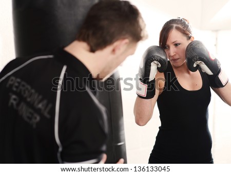 Woman working out with personal trainer on punch bag in gym