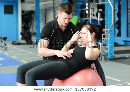 Personal trainer helping young woman in gym