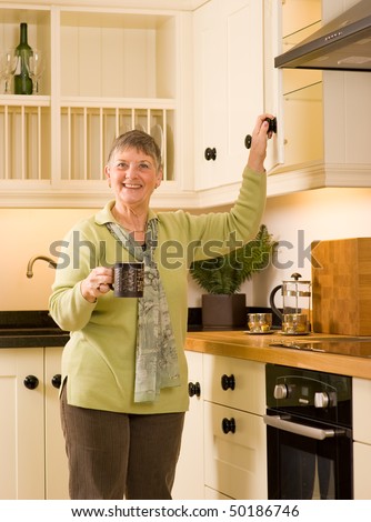 Happy senior woman making a drink in modern designer kitchen