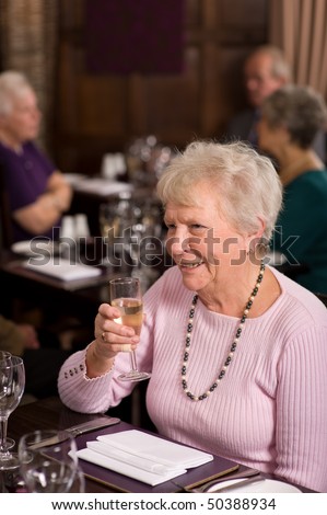 Older mature senior lady celebrating in posh restaurant