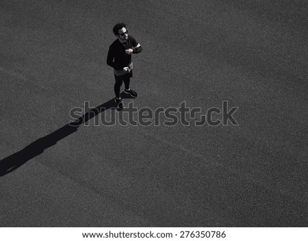 Muscular sportsman model ready for his run on a black asphalt. Fit strong man on his mark to start running. Determined athlete outdoors.