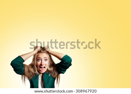 Portrait headshot very sad depressed, stressed disappointed gloomy young man head on hands screaming in despair isolated on yellow wall background. Human emotion facial expression reaction