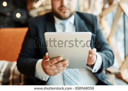 Silhouette of cropped shot of a businessman working using digital tablet, man\'s hands using touch pad in a coffee shop, man at his workplace using technology.