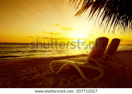 Art Sunrise view at resort. Relaxing holiday landscape. Two chaise loungue on beach with palm tree.