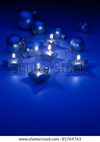 burning Christmas candles and ornaments on a blue background