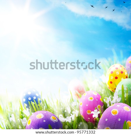 Colorful Easter eggs decorated with flowers in the grass on blue sky background
