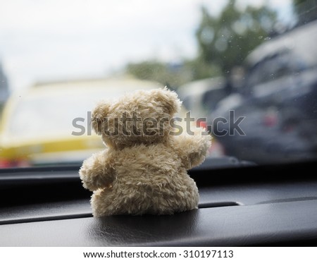 teddy bear sitting on a car in the city