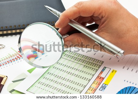 magnifying glass in hand and working paper chart