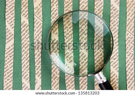 Collage cut from newspaper  and magnifying glass on green background