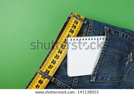 jeans with meter belt slimming and notebook in pocket on the green background