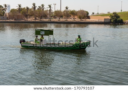 SHARJAH, UAE - OCTOBER 28, 2013: Workers in uniform on the boat cleaning bay.