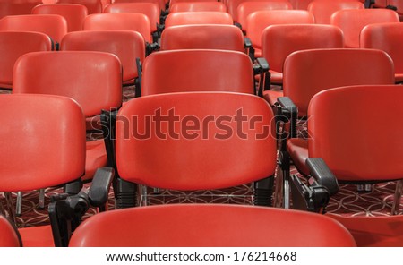 red recliners stand rows in an empty conference hall