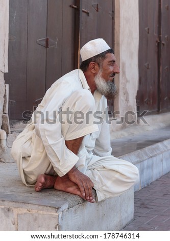 DUBAI, UAE-OCTOBER 30: Old man sitting on the stone steps of the old city of Bar Dubai on October 30, 2013. It is the oldest part of the city in Dubai, UAE
