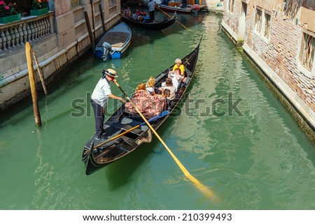 VENICE, ITALY - 26 JUNE, 2014: Gondolier rides gondola. The profession of gondolier is controlled by a guild, which issues a limited number of licenses