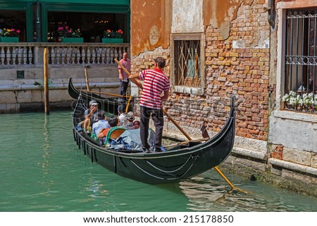VENICE, ITALY - JUNE 26, 2014: Gondolier rides gondola. The profession of gondolier is controlled by a guild, which issues a limited number of licenses