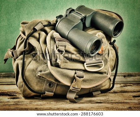 Old travel backpack and binoculars on the floor. Toned