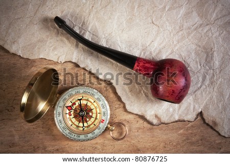 compass and a tobacco pipe on a wooden board, still-life