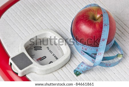 apple and measuring tape on the floor scales isolated on white