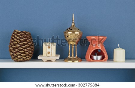 Decorative candles on white  shelf on blue wallpaper background