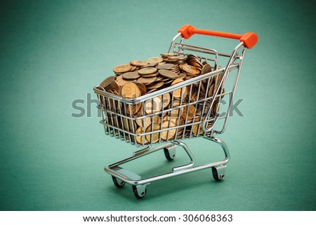 Shopping trolley with coins on a green background