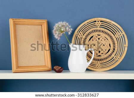 photoframe and vase with a flower on white  shelf on blue wallpaper background