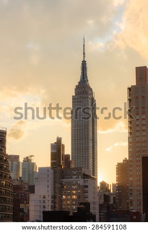 View of the Empire state building at sunset, golden orange clouds in the background - April 22, 2015, midtown Manhattan, New York city, NY, USA