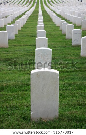 Rows of white tombstones in cemetery in Queens. Single first row tombstone in focus, others progressively out of focus - July 2, 2015, National cemetery, New York City, NY, USA