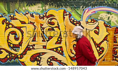 SAN FRANCISCO/CA/USA - CIRCA AUGUST 2010: Elderly Chinese woman passes a wall of graffiti in Chinatown in August, 2010. It\'s one of North America\'s largest Chinatowns - and the oldest in the USA.