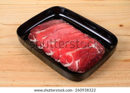 Lean meat in black tray on wooden background.